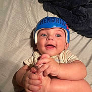 Hendrix joined the competition — help win amazing prizes! baby, helmet, blue_helmet, smiling, infant, hands, feet, bed, blanket, white_clothing, happy, cute, lying_down, child, indoor, person, skin, headwear, expression, young