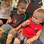 child, children, boy, toddler, bench, shirt, shorts, sitting, outdoor, daylight, person, curious, focused, red_shirt, plaid_shorts, footwear, unicorn, blonde_hair, green_bench, casual