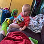 toddler, child, indoor, couch, blanket, toy, person, socks, shirt, wall, poster, floor, doorway, room, furniture, casual, relaxed, home, colorful, cozy