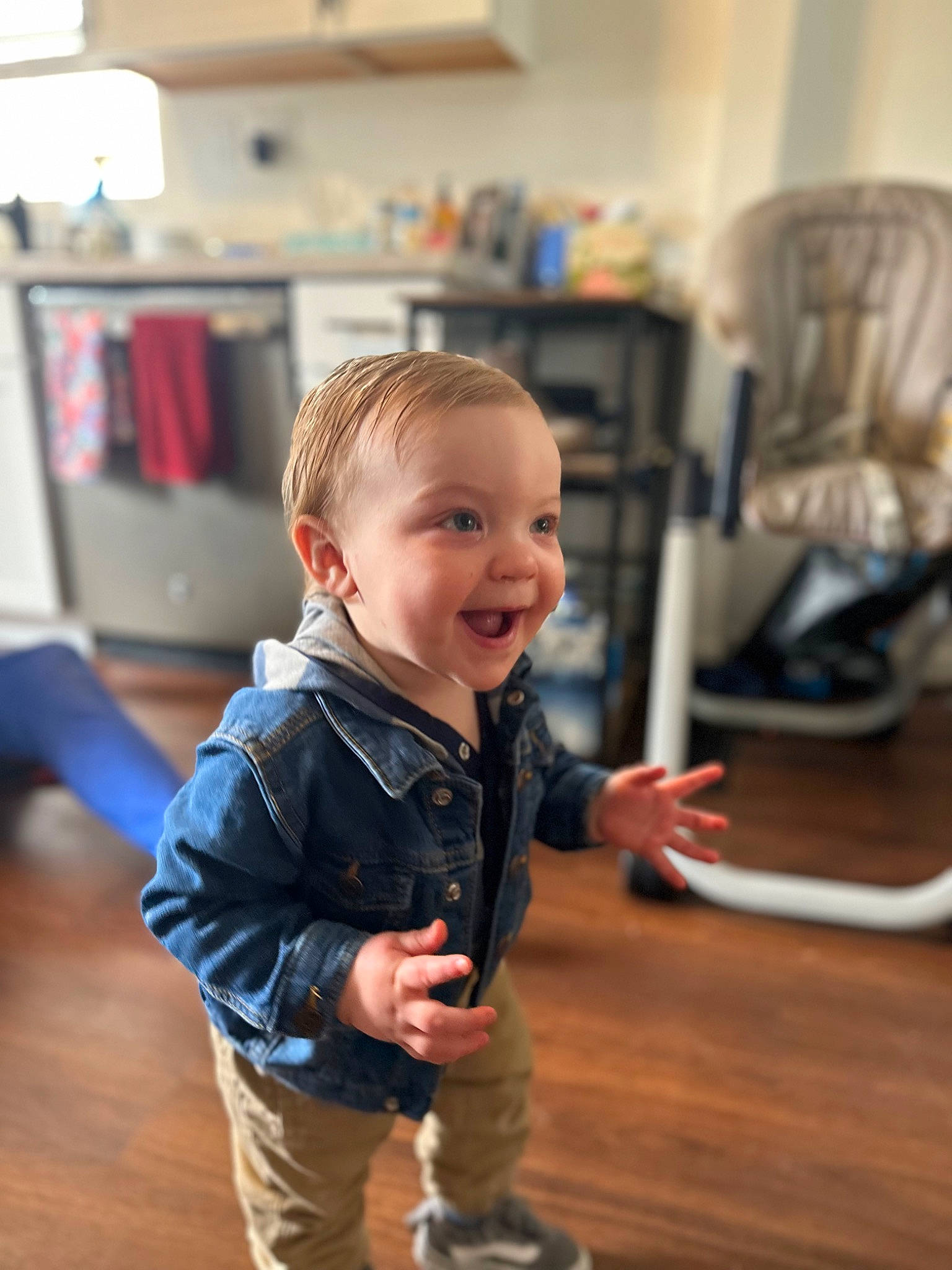 Bodhi is registered to the contest to win money with this photo: baby_toddler_clothing, chair, child, drawer, eye, floor, flooring, fun, happy, hardwood, joy, person, room, shelf, sitting, sleeve, smile, standing, toddler, varnish