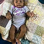 Jamoni is registered to the contest to win money with this photo: baby, infant, onesie, patchwork_quilt, blanket, clothing, person, child, barefoot, cute, laying_down, indoor, textile_pattern, purple, gray, skin, face, hand, foot, comfort