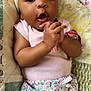 baby, infant, headband, bow, cute, expression, hands, clasped, pink_shirt, floral_shorts, quilt, blanket, indoor, portrait, child, person, sleepwear, smiling, closeup, cozy