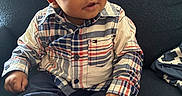 Bryson is registered to the contest to win money with this photo: baby, child, infant, portrait, sitting, couch, indoor, plaid_shirt, shirt, pants, sneakers, shoes, face, eyes, hair, curious, looking_up, hands, furniture, photography