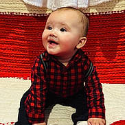 Jaxon is registered to the contest to win money with this photo: baby, child, smiling, sitting, red_checkered_shirt, black_pants, white_socks, blanket, red_blanket, white_blanket, cute, happy, indoors, portrait, infant, face, hand, looking_up, cozy, warm
