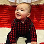 baby, child, smiling, sitting, red_checkered_shirt, black_pants, white_socks, blanket, red_blanket, white_blanket, cute, happy, indoors, portrait, infant, face, hand, looking_up, cozy, warm