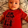 baby, infant, red_onesie, darth_vader, cartoon, text, trouble_maker, face, eyes, lying_down, patterned_background, child, cute, serious_expression, clothing, indoors, person, portrait, young_child, toddler