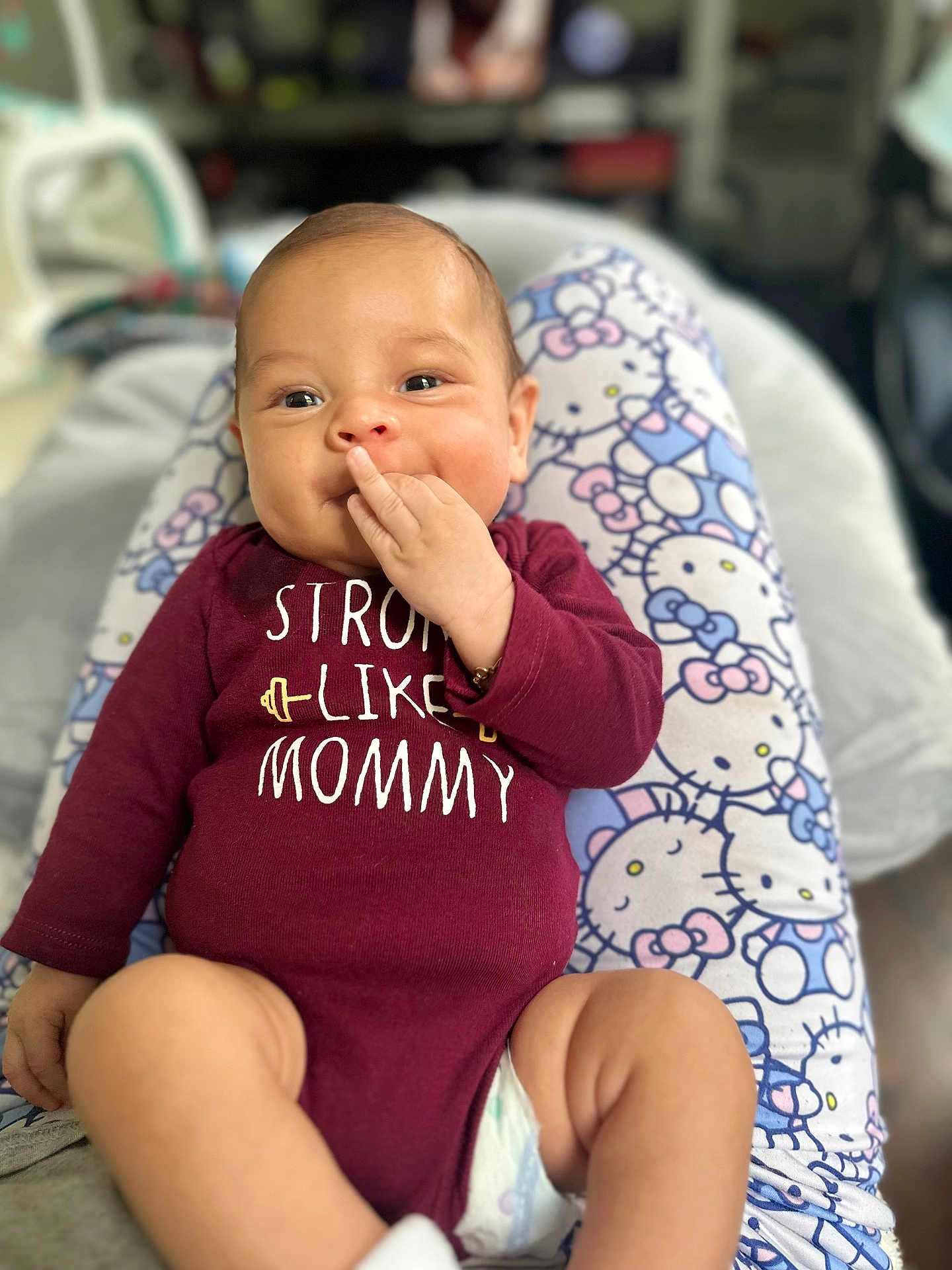 Matthew is registered to the contest to win money with this photo: baby, child, closeup, cute, face, hand_on_face, happy, hello_kitty, indoor, infant, legs, maroon_clothing, onesie, pajamas, person, portrait, sitting, skin, smiling, text_on_clothing