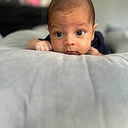 Matthew joined the competition — help win amazing prizes! baby, infant, face, eyes, hands, pillow, soft_surface, curious, lying_down, indoors, portrait, child, skin, closeup, head, expression, young, person, sleepwear, focus