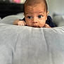 baby, infant, face, eyes, hands, pillow, soft_surface, curious, lying_down, indoors, portrait, child, skin, closeup, head, expression, young, person, sleepwear, focus