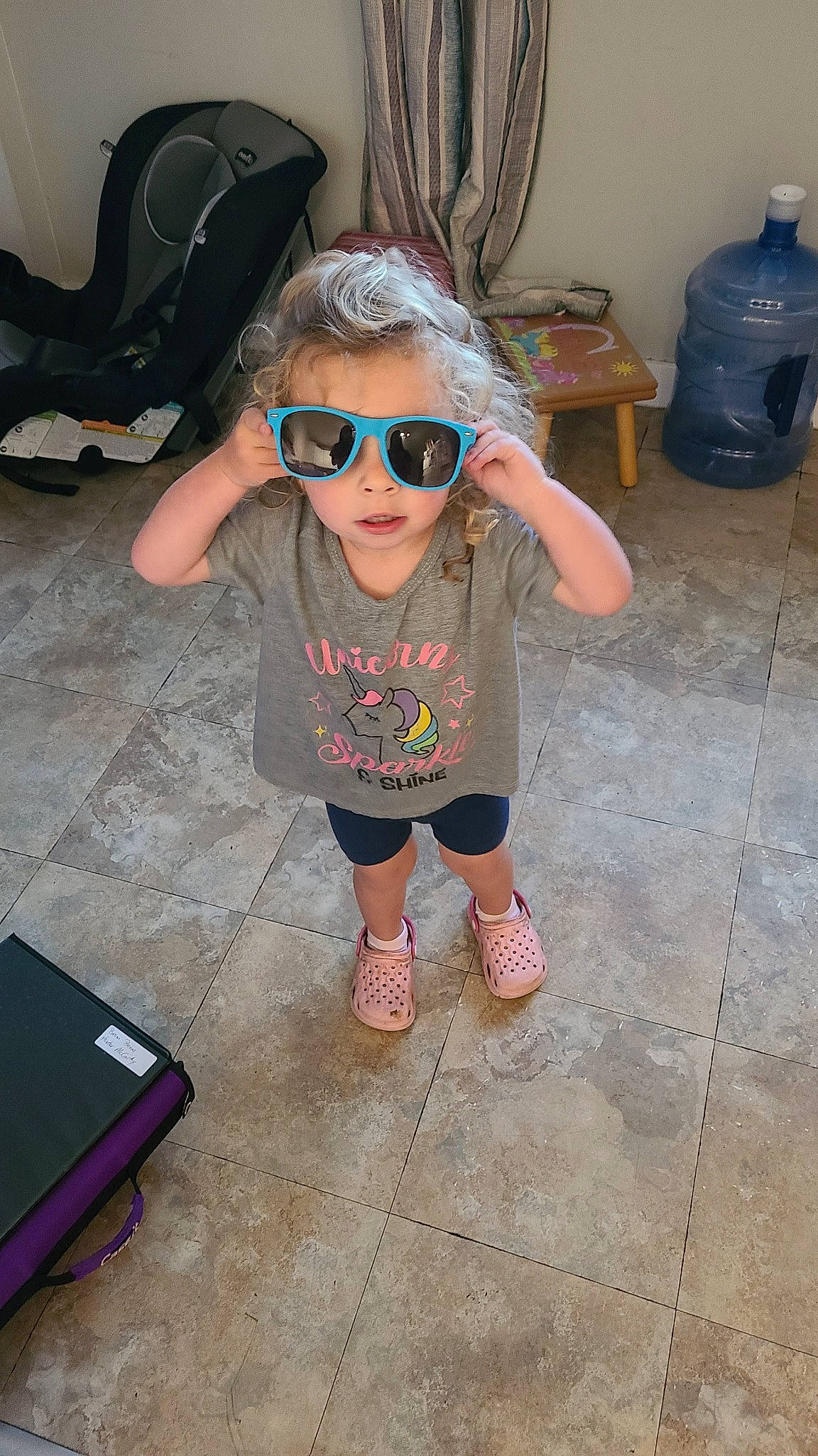 Cadence is registered to the contest to win money with this photo: event, eyewear, flip_flops, floor, flooring, foot, fun, glasses, goggles, happy, head, human_leg, leisure, mouth, person, sandal, smile, sunglasses, thigh, toddler