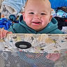 baby, toddler, child, playpen, blanket, blue_hoodie, smile, face, indoor, toy, animal_print, hand, fabric, cozy, young_child, cute, expression, person, infant, home
