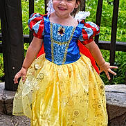 Aitana is registered to the contest to win money with this photo: child, girl, smiling, princess_costume, snow_white, dress, yellow_skirt, blue_bodice, red_sleeves, outdoor, greenery, stone_path, wooden_railings, happy, playful, portrait, cute, fashion, costume, childhood