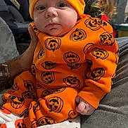 Alexander joined the competition — help win amazing prizes! baby, child, infant, orange_outfit, pumpkin_pattern, hat, blanket, polar_bear_design, cozy, indoor, person, cute, sitting, hand, long_hair, background, clothing, portrait, family, home