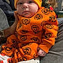 baby, child, infant, orange_outfit, pumpkin_pattern, hat, blanket, polar_bear_design, cozy, indoor, person, cute, sitting, hand, long_hair, background, clothing, portrait, family, home