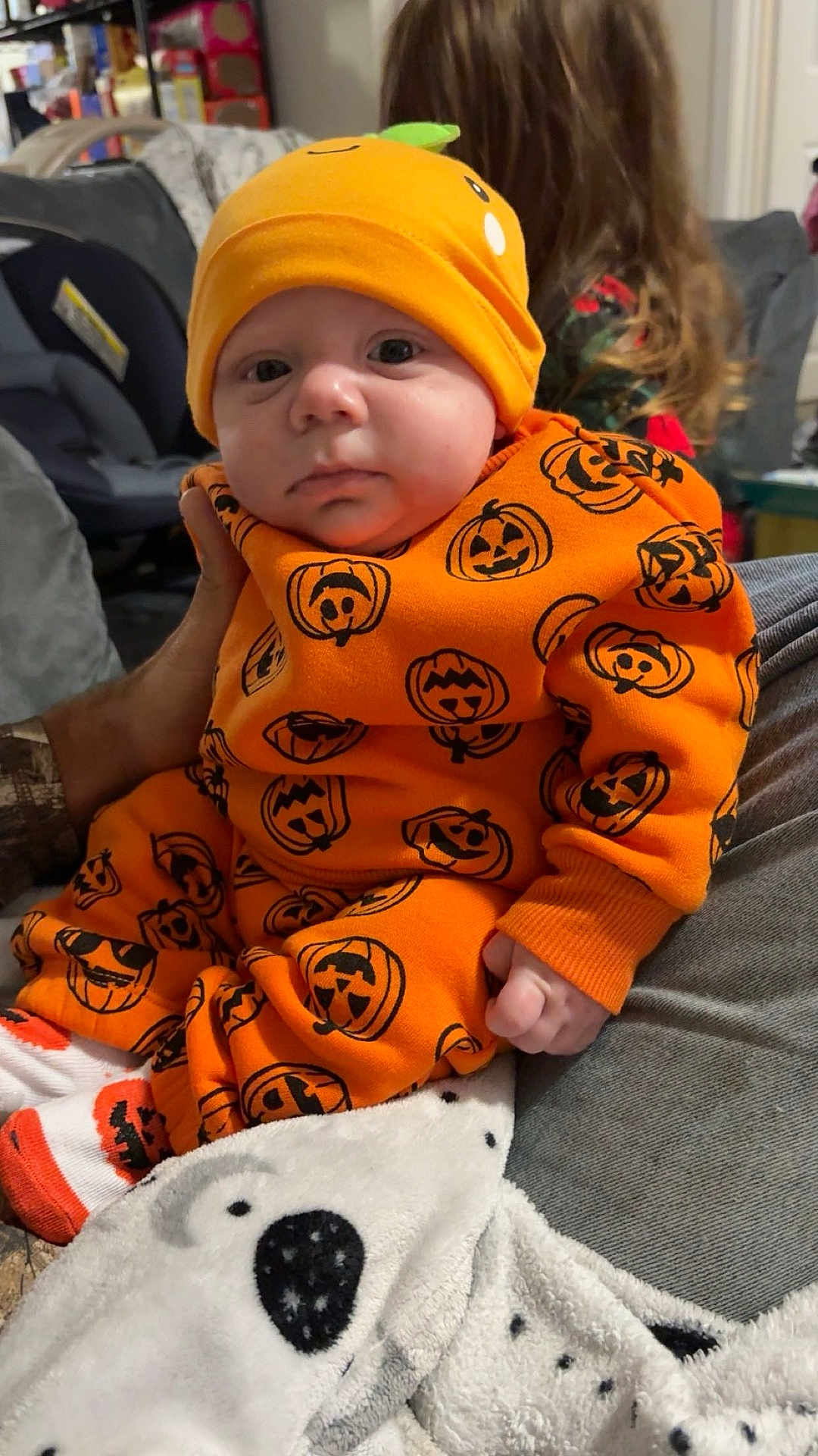 Alexander joined the competition — help win amazing prizes! baby, child, infant, orange_outfit, pumpkin_pattern, hat, blanket, polar_bear_design, cozy, indoor, person, cute, sitting, hand, long_hair, background, clothing, portrait, family, home