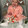 baby, child, smiling, headband, pink_coat, floral_dress, white_tights, carrot_toys, bunny_decorations, blanket, milestone, nine_months, cute, portrait, indoor, happy, sitting, infant, decor, celebration