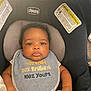 baby, infant, car_seat, chicco, bib, clothing, face, child, cute, serious_expression, text_on_clothing, seatbelt, safety_warning, indoor, person, head, arm, skin, young_child, closeup