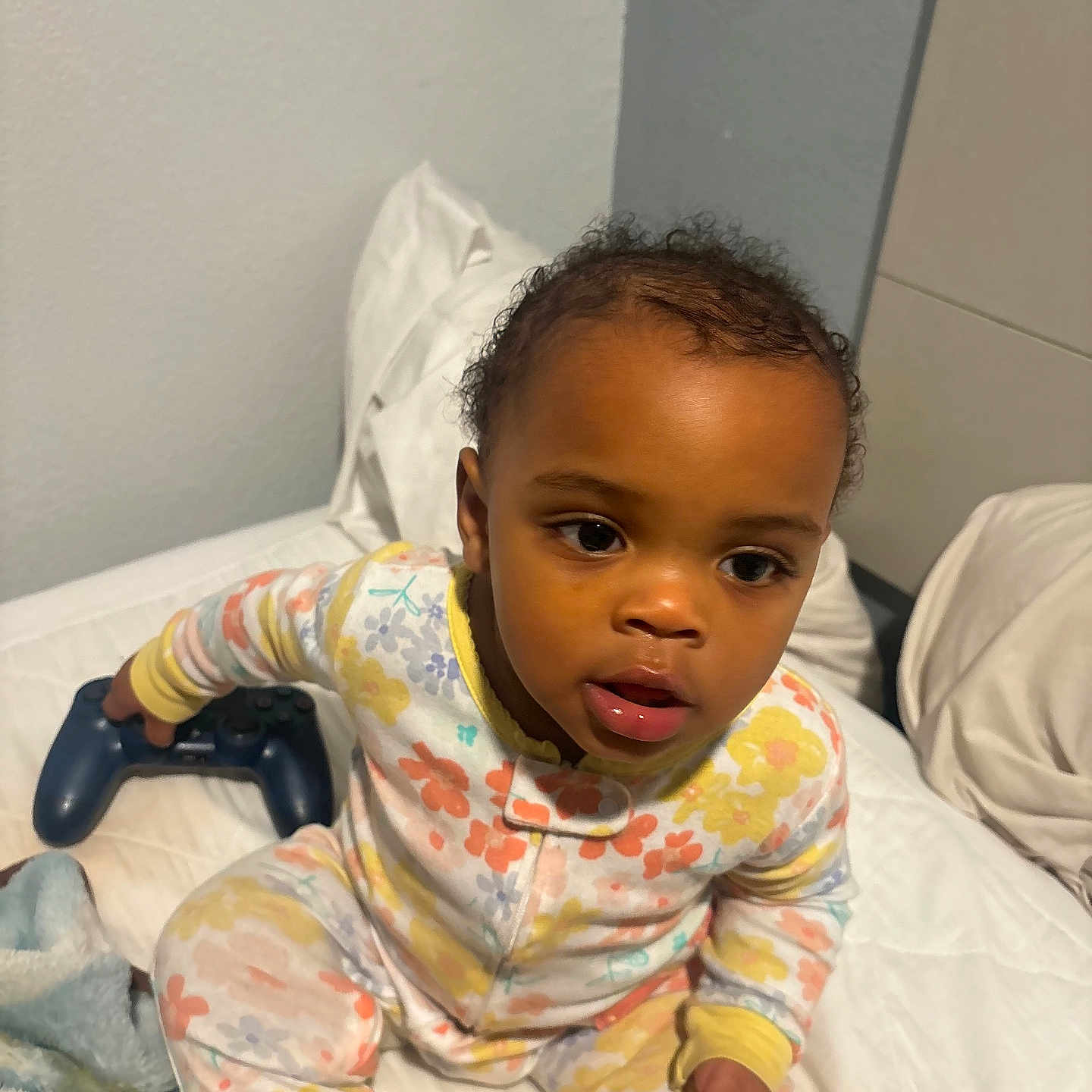 Emiyana joined the competition — help win amazing prizes! bed, blanket, child, colorful, comfort, controller, cozy, curly_hair, cute, expression, furniture, home, indoor, pajamas, person, playing, sitting, toddler, video_game_controller, young_child