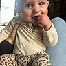 baby, child, infant, smiling, hand, leopard_print, clothing, long_sleeve, pants, person, indoor, window, light, happy, cute, skin, head, face, sitting, holding