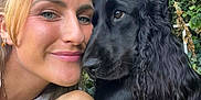 Kida participe au concours pour gagner de l'argent avec cette photo : woman, dog, black_dog, pet, hug, outdoor, greenery, hedge, smile, face, long_hair, earrings, bracelet, affection, closeup, portrait, nature, friendship, head, expression