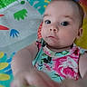 baby, child, infant, face, hand, floral_clothing, playmat, colorful, curious, indoors, person, portrait, closeup, young_child, skin, eyes, expression, background, toy, bright_colors