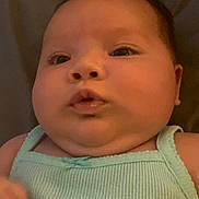 Ariya is registered to the contest to win money with this photo: baby, child, face, portrait, close_up, infant, skin, expression, person, clothing, tank_top, cute, chubby_cheeks, mouth, eyes, head, lying_down, indoors, soft_light, background