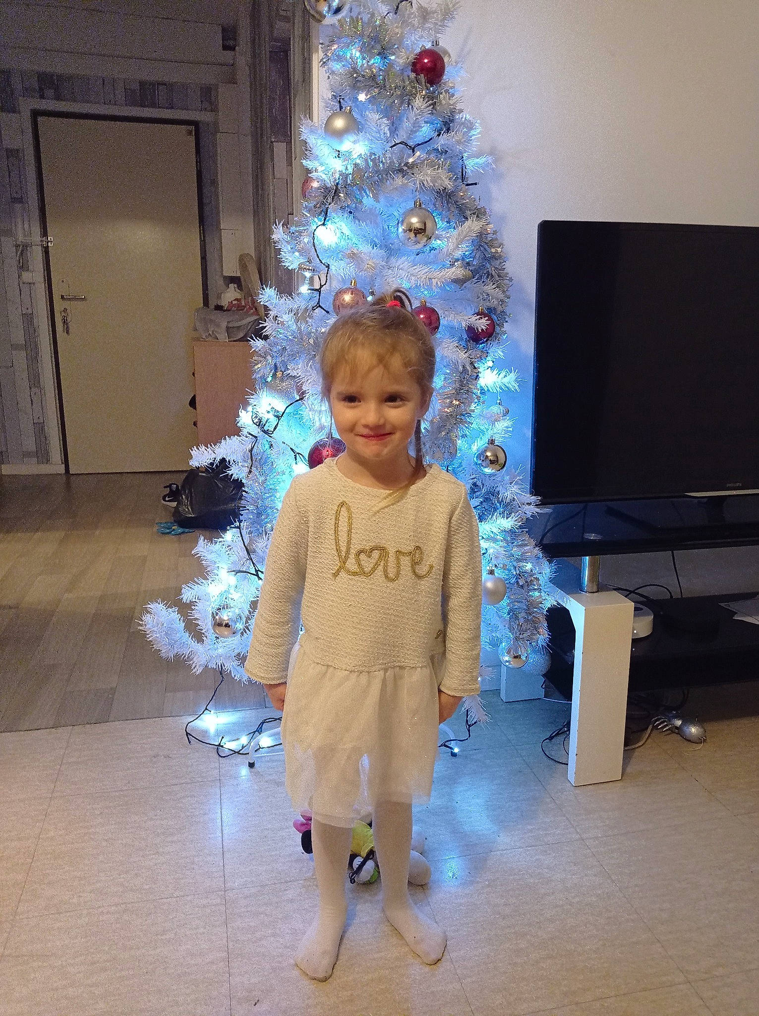 Aélys participe au concours pour gagner de l'argent avec cette photo : christmas, christmas_decoration, christmas_ornament, christmas_tree, door, event, evergreen, flooring, fun, happy, holiday, holiday_ornament, home_appliance, joy, ornament, person, plant, standing, television, toddler