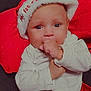 Aurora is registered to the contest to win money with this photo: baby, celebration, child, christmas, clothing, cushion, cute, face, festive, headwear, holiday, holiday_season, indoors, infant, portrait, red_skirt, santa_hat, smiling, thumb_sucking, white_top