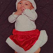 Aurora is registered to the contest to win money with this photo: baby, blanket, cheerful, child, christmas, cute, feet, festive, holiday, holiday_costume, indoors, infant, lying_down, pom_pom, portrait, red_skirt, santa_hat, small_hands, socks, white_top