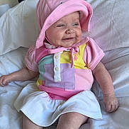 Blair is registered to the contest to win money with this photo: baby, bed, child, clothing, colorful, cute, happy, hat, indoors, infant, person, pink, portrait, shirt, sitting, skirt, smile, socks, soft, white