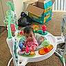 Zoya is registered to the contest to win money with this photo: baby, infant, activity_jumper, toy, pink_clothing, carpet, pampers_box, indoor, black_bag, playtime, child, floor, colorful_toys, curious, young_child, home, plastic_toys, seat, person, living_space