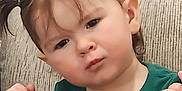 Fiadh is registered to the contest to win money with this photo: toddler, child, pigtails, green_shirt, couch, indoor, portrait, serious_expression, baby, person, face, hair, skin, sitting, young_child, furniture, casual_clothing, cute, closeup, home