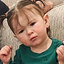 toddler, child, pigtails, green_shirt, couch, indoor, portrait, serious_expression, baby, person, face, hair, skin, sitting, young_child, furniture, casual_clothing, cute, closeup, home