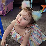 Fiadh is registered to the contest to win money with this photo: toddler, child, toy, carpet, dress, headband, pom_poms, colorful, indoor, playing, curious, smiling, cute, person, furniture, car, floor, home, happy, young