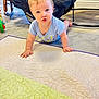 baby, blue_eyes, blue_onesie, car_seat, carpet, child, crawling, curious, floor, floor_mat, furniture, home, indoor, infant, person, quilt, soft_light, toy, wooden_chair, young_child