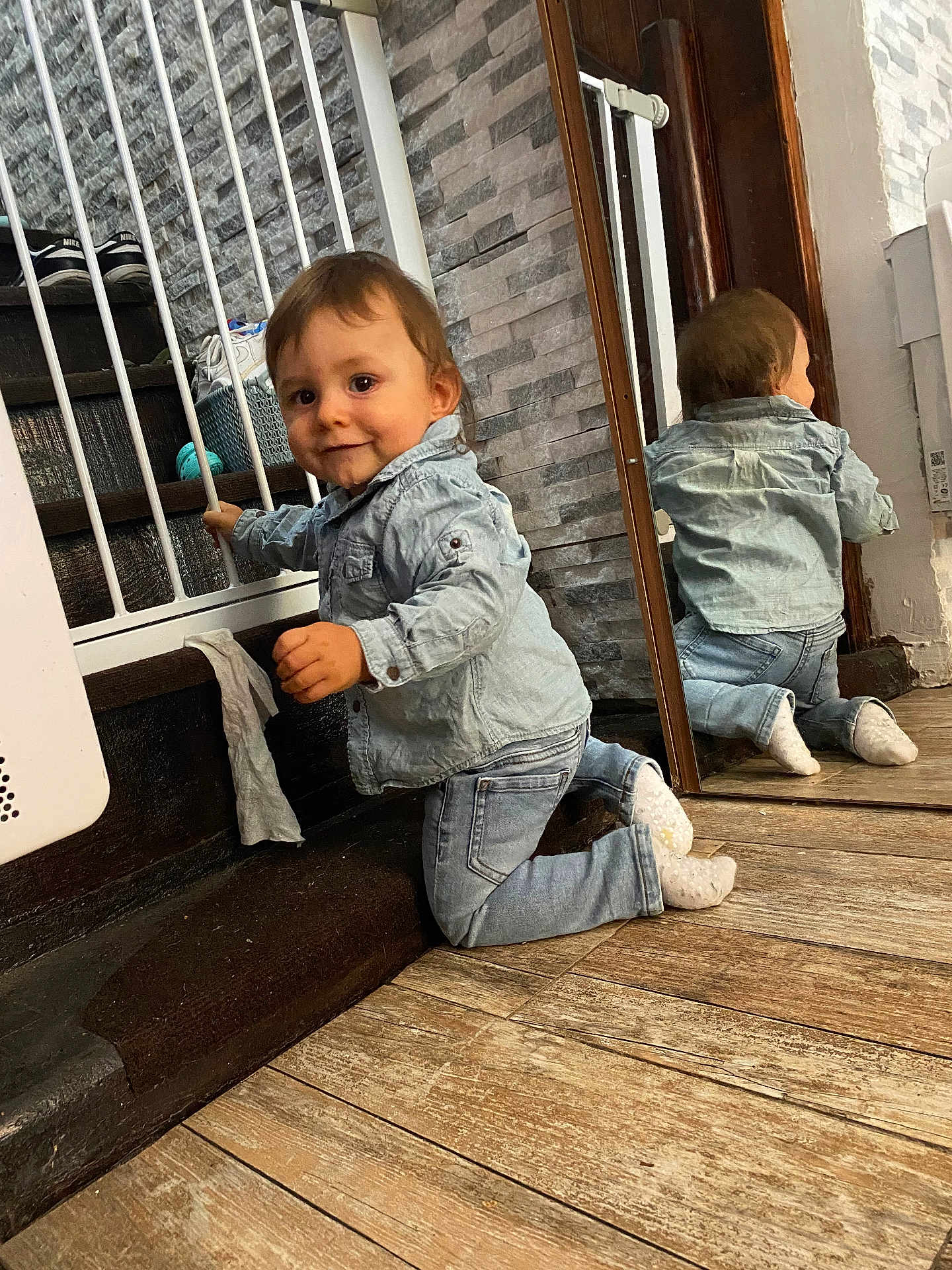 Alessyo a rejoint le concours — aidez-le/la à gagner de superbes lots ! toddler, child, denim_jacket, denim_jeans, socks, mirror, wooden_floor, stair_gate, indoor, smile, reflection, wall, curious, baby, playful, face, kneeling, person, home, casual_clothing