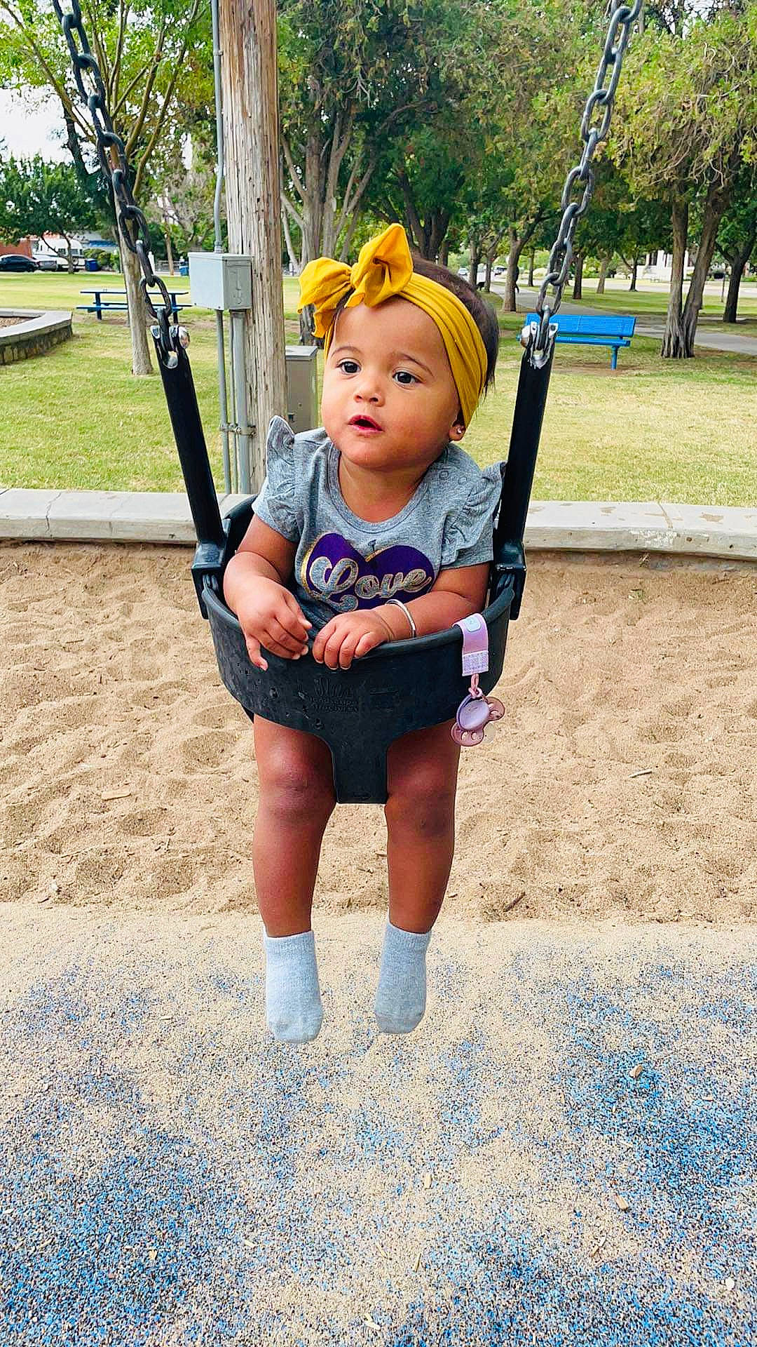Hallie Rae is registered to the contest to win money with this photo: baby, baby_toddler_clothing, blue, city, electric_blue, face, grass, happy, hat, headwear, human_settlement, leisure, outdoor_play_equipment, person, plant, playground, recreation, sun_hat, swing, t_shirt