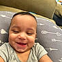 baby, smiling, infant, pillow, arrows, hearts, clothing, gray_shirt, cute, happy, face, child, indoors, closeup, person, skin, head, expression, joy, young