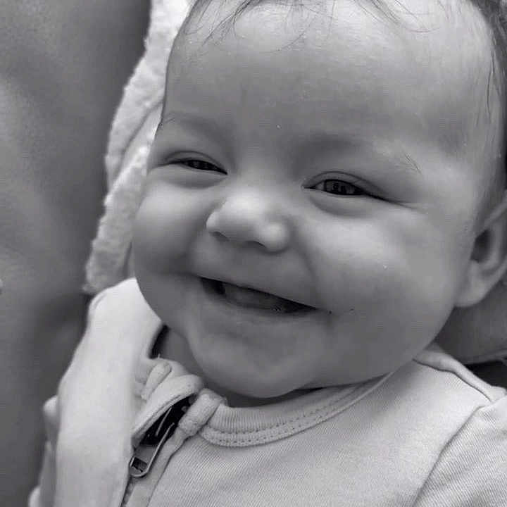 Rommy participe au concours pour gagner de l'argent avec cette photo : baby, black_and_white, blanket, child, close_up, clothing, comfort, cozy, cute, face, happy, head, indoor, infant, person, portrait, smiling, soft_texture, young, zipper