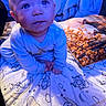 adorable, baby, bed, bedding, blanket, blue_tint, close_up, cute, drool, eyes, face, hands, indoor, infant, looking_up, onesie, patterned_pillow, pillow, sitting, soft_lighting
