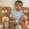baby, child, teddy_bear, plush_toy, striped_clothing, blue_and_white, sitting, cute, indoors, portrait, soft_toys, expression, bracelet, white_background, buttoned_shirt, shorts, infant, large_eyes, pout, young