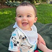Declan joined the competition — help win amazing prizes! baby, child, smiling, outdoor, grass, blanket, bib, shirt, mickey_mouse, happy, cute, sitting, nature, greenery, sunlight, infant, portrait, face, cheerful, daylight