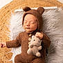 baby, newborn, sleeping, knitwear, brown, bear_ears, plush_toy, cushion, white_fur, woven_mat, cute, infant, portrait, soft_texture, hand, closed_eyes, child, cozy, indoors, resting
