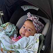 Leila joined the competition — help win amazing prizes! baby, car_seat, blanket, pacifier, headband, infant, child, portrait, indoors, soft_fabric, clothing, seatbelt, cute, young_child, car_interior, canopy, resting, wrapped, face, looking