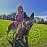 blue_sky, canine, casual_clothing, child, daytime, dog, field, fun, grass, greenery, happy, leisure, nature, outdoor, pet, playful, portrait, smiling, sunlight, young