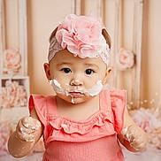 Charlotte joined the competition — help win amazing prizes! baby, child, girl, pink_dress, headband, flower, cake_frosting, messy, hands, face, portrait, indoor, decorations, soft_colors, cute, young_child, celebration, smiling, closeup, adorable