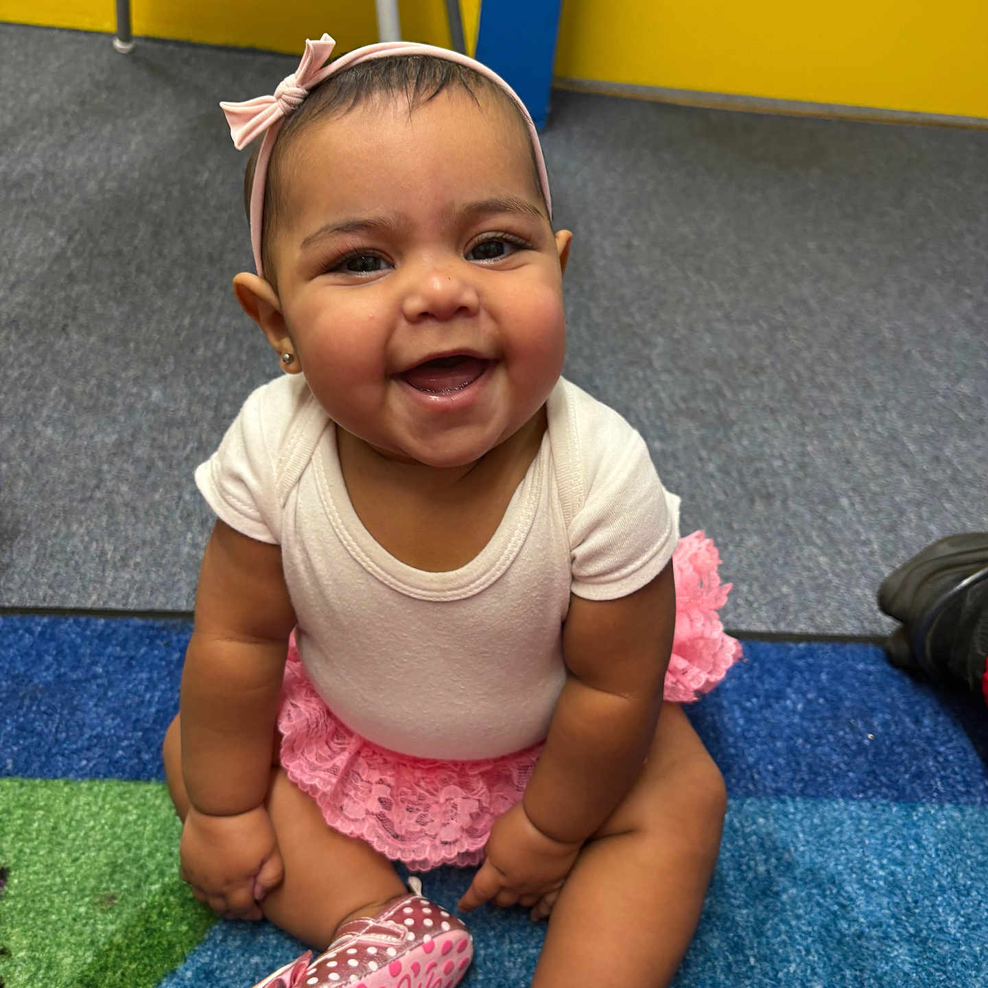 Emireya Lima is registered to the contest to win money with this photo: baby, child, smiling, sitting, headband, pink, skirt, lace, shoe, play_mat, indoor, colorful, happy, cute, person, floor, young_child, portrait, infant, clothing