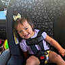 Ariella joined the competition — help win amazing prizes! child, toddler, car_seat, smile, purple_shirt, bow, hair_accessory, safety_harness, car_interior, seatbelt, happy, cute, young_child, infant, automobile, seat, travel, baby, playful, portrait