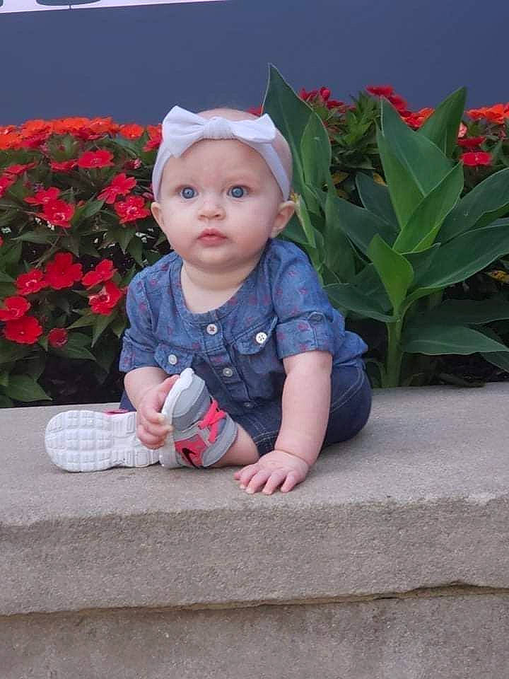 Paris is registered to the contest to win money with this photo: baby, baby_toddler_clothing, cap, carmine, child, flower, fun, garden, grass, happy, headwear, magenta, outerwear, pattern, person, petal, pink, plant, sitting, sleeve