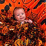 baby, infant, blanket, orange, halloween, tinsel, decoration, face, smile, cute, festive, holiday, child, celebration, cozy, soft, indoors, portrait, happy, person